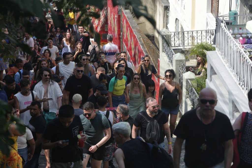 Dua Lipa com camisa verde e amarela, bermuda jeans, no meio da multidão, na escadaria Selaron, na Lapa, RJ