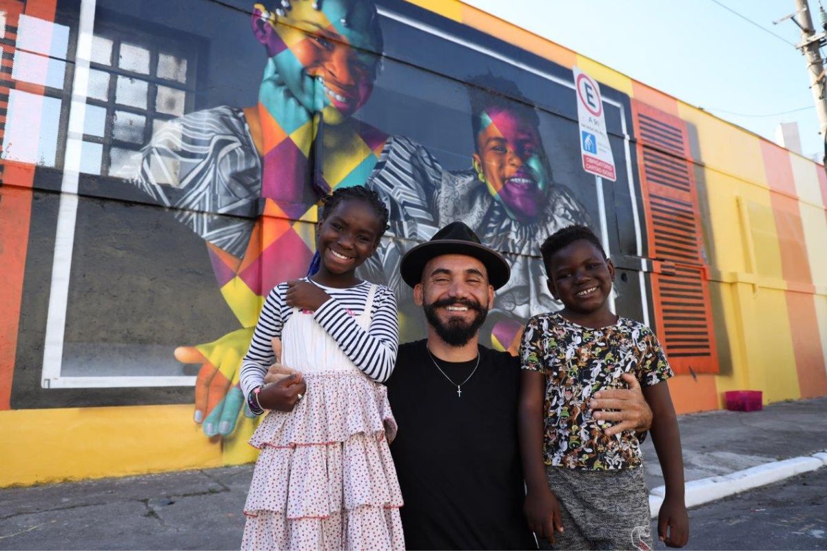 Eduardo Kobra com os angolanos Delfina e Victor, em frente ao mural assinado por ele, Janelas Abertas para o Mundo