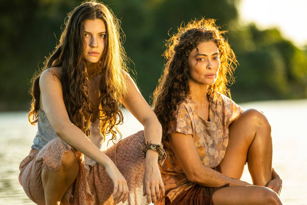 juma (alanis guillen) e maria marruá (juliana paes) ajoelhadas juntas em pantanal