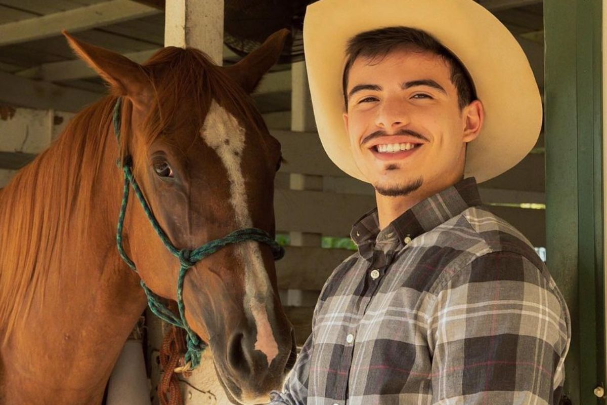 thomaz costa com roupa de fazendeiro posando ao lado de cavalo