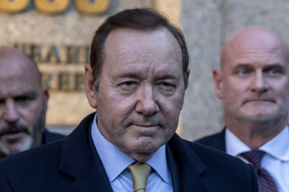 Kevin Spacey de terno saindo do tribunal