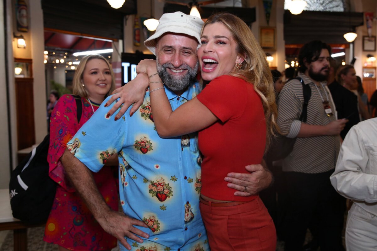 Mauro Mendonça Filho de boné branco camisa azul estampada, abraçado à Grazi Massafera, que está de vermelho