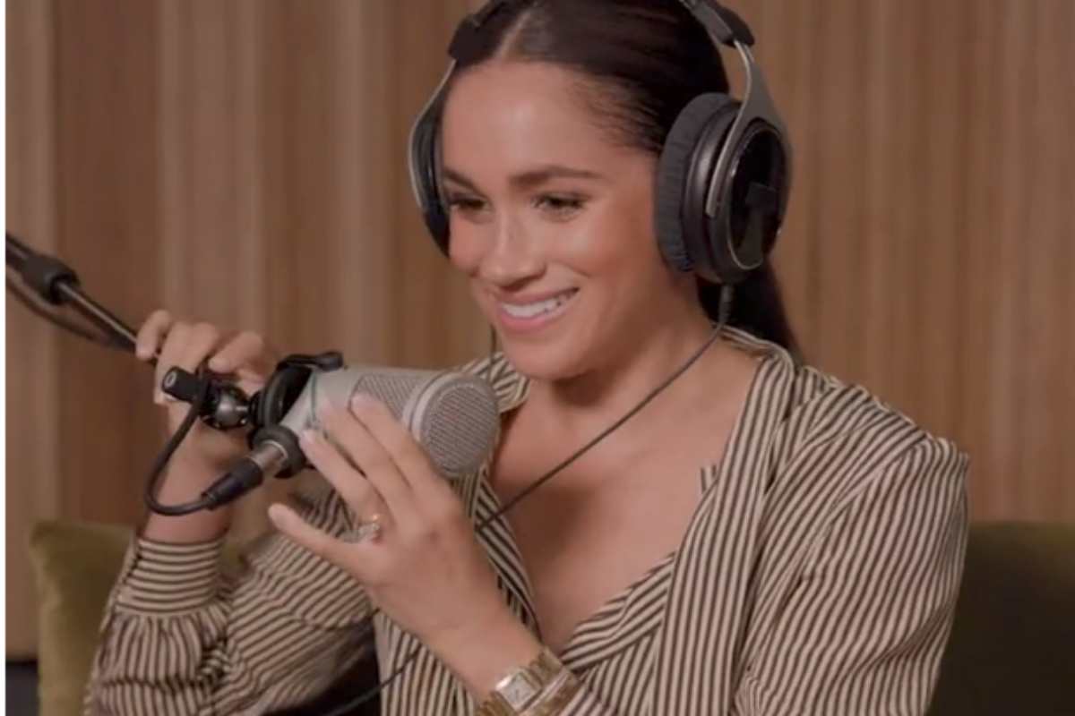 Meghan Markle falando ao microfone em seu podcast