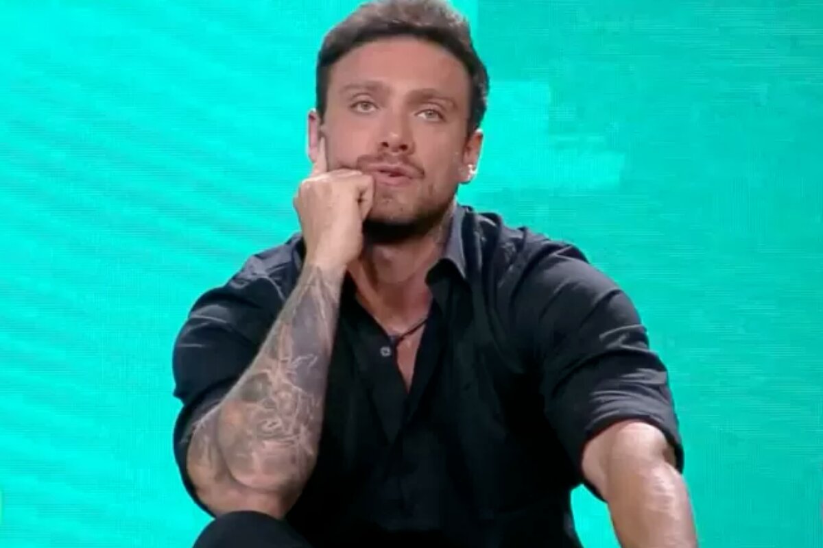 Vini Buttel de camisa preta, com o punho cerrado no queixo