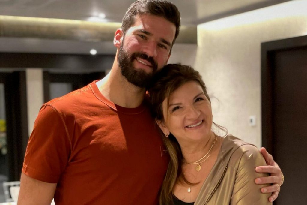 Alisson de camisa vermelha, abraçado à mãe, Magali de camisa marrom