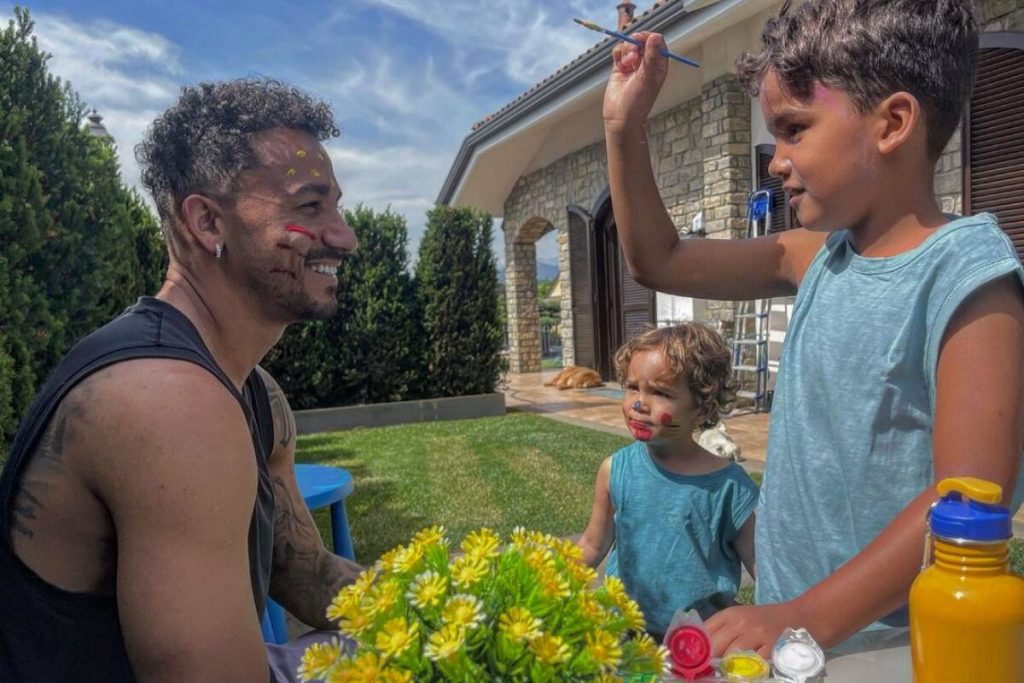 Danilo Luiz sentado brincando com os dois  filhos