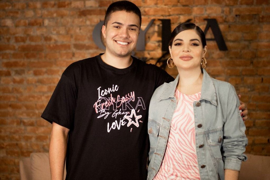 Felipe Dutra de camisa preta e Gkay de jaqueta jeans e camisa rosa