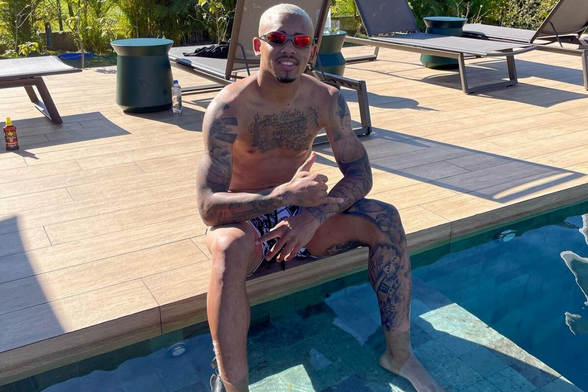 Gabriel Jesus sentado à beira da piscina, sem camisa