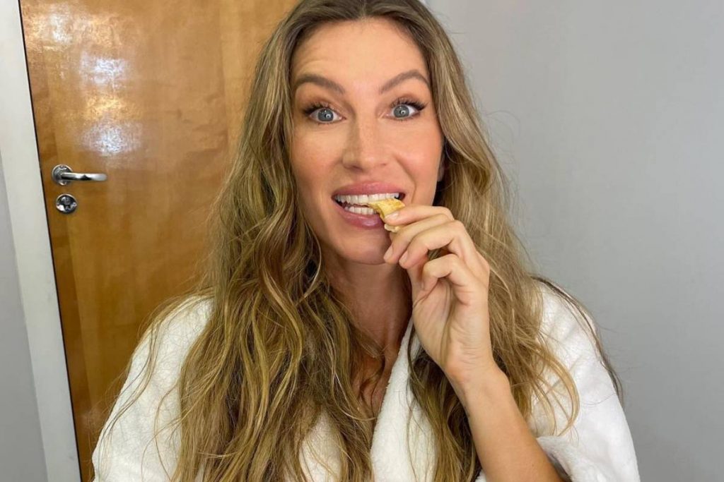 gisele bundchen mordendo petisco posando com roupa branca