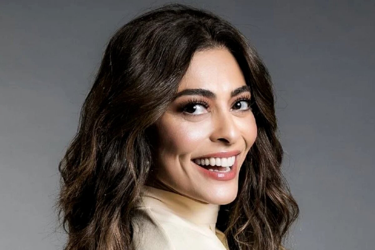 Juliana Paes sorrindo, de perfil, camisa branca de gola alta