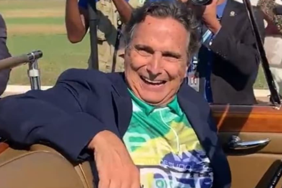 nelson piquet posando em carro com camiseta da bandeira do brasil