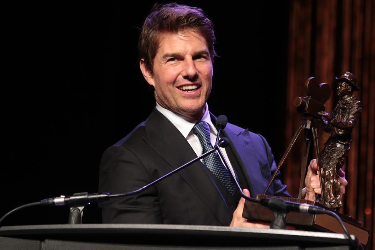 tom cruise segurando troféu em discurso durante premiação