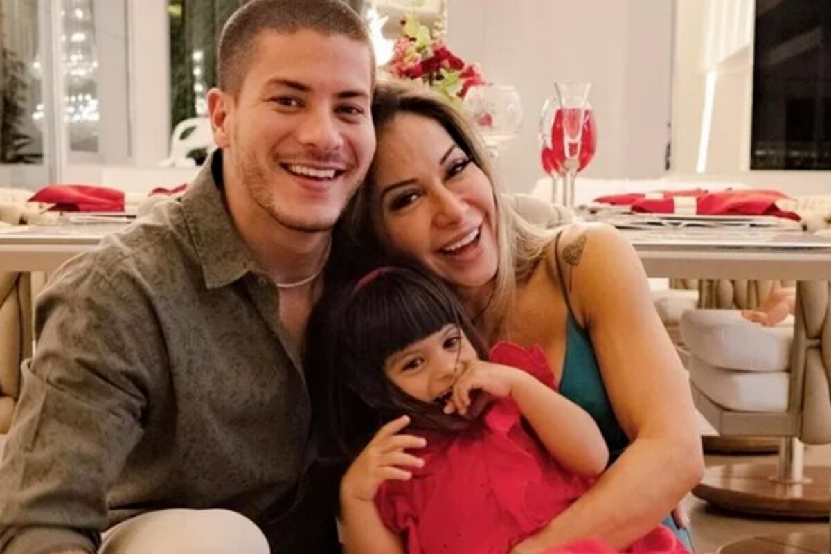 Arthur Aguiar, Maira Cardi e Sophia abraçados e sorrindo, sentados