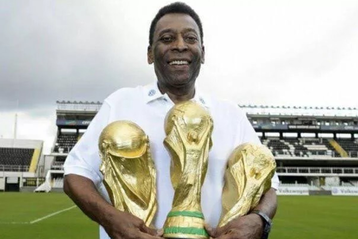 pelé segurando três troféus da copa do mundo