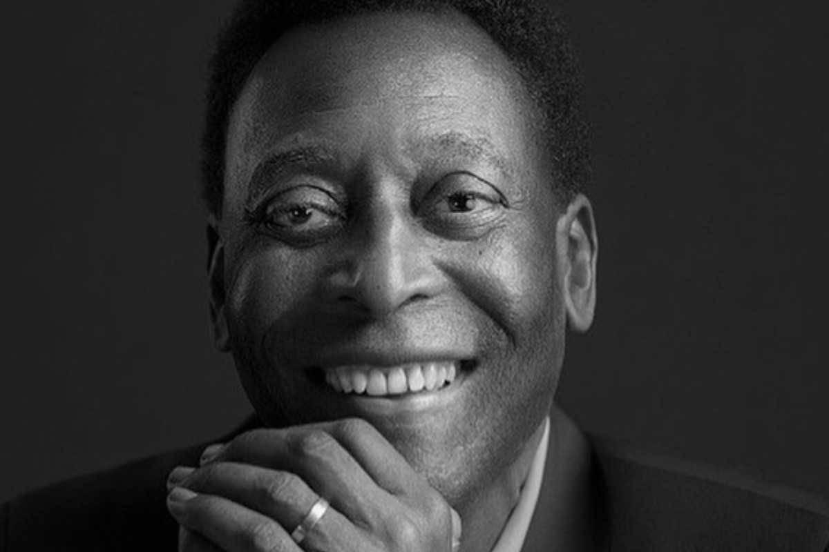 pelé sorrindo de terno em foto preta e branca