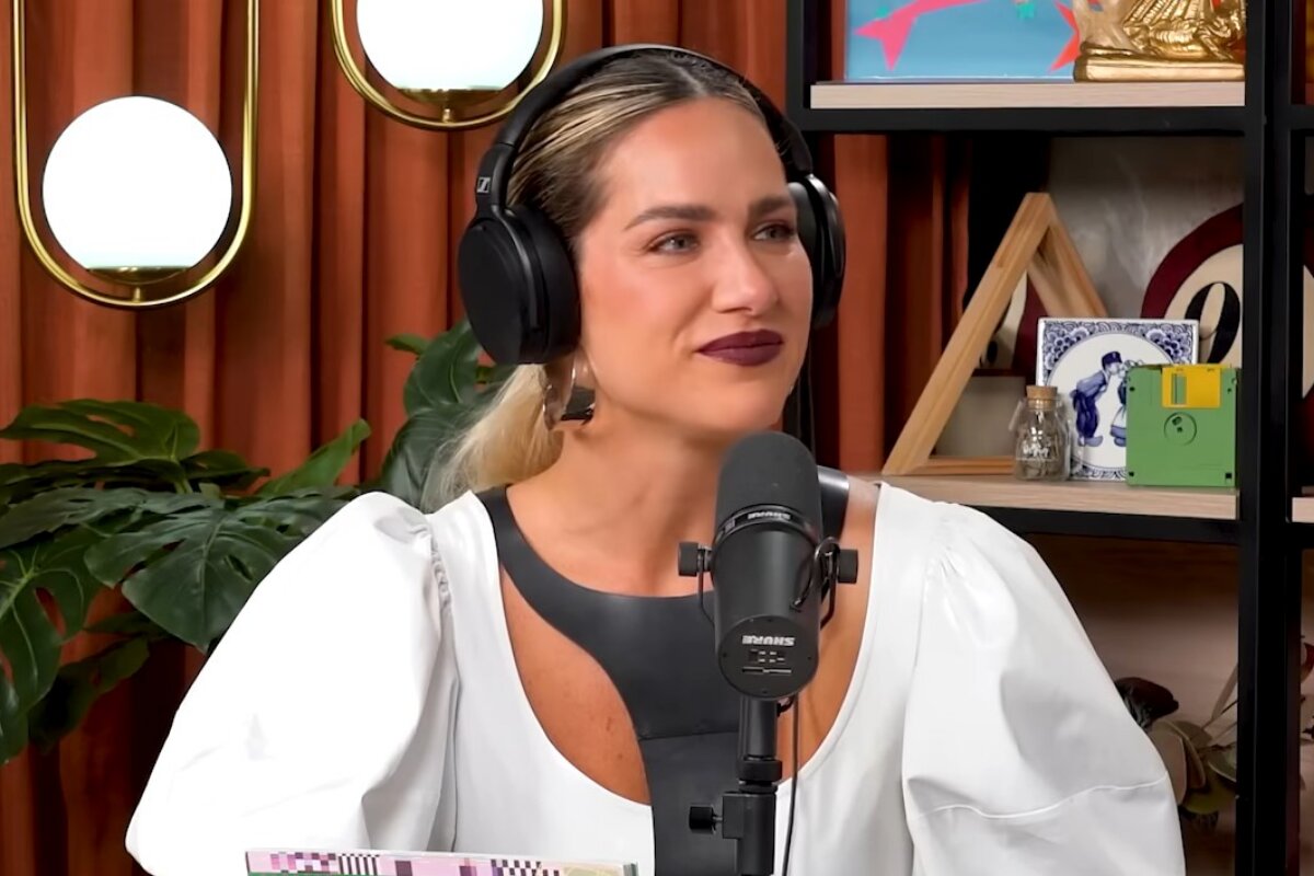 Giovanna Ewbank de branco, no estúdio de podcast, com fone no ouvido