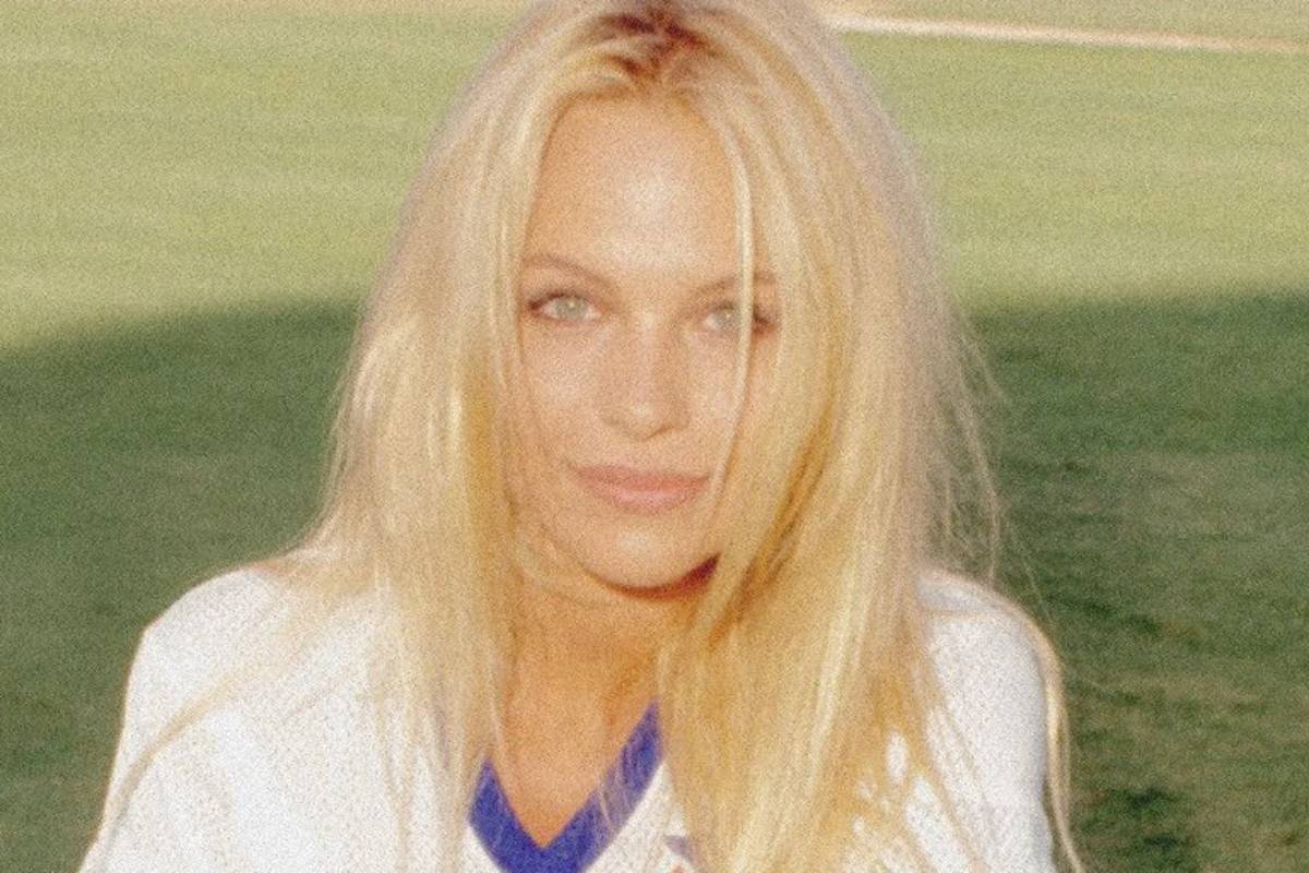 pamela anderson sentada no gramado em dia de sol