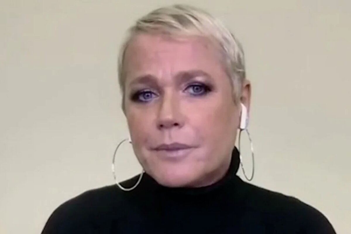 Xuxa de camisa de gola alta preta, argolas nas orelhas