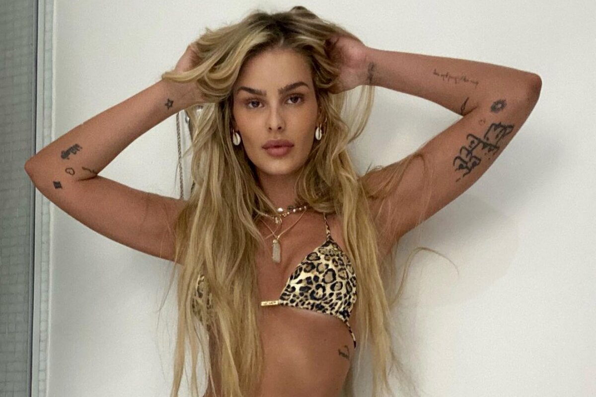 Yasmin Brunet de biquíni animal print, com as mãos no cabelo