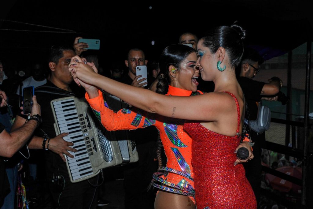 Juliette de vestido vermelho e Mari Antunes de body laranja