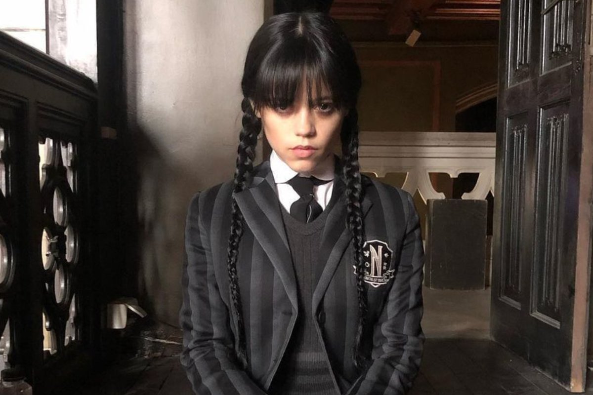 jenna ortega como wandinha sentada em escada na série