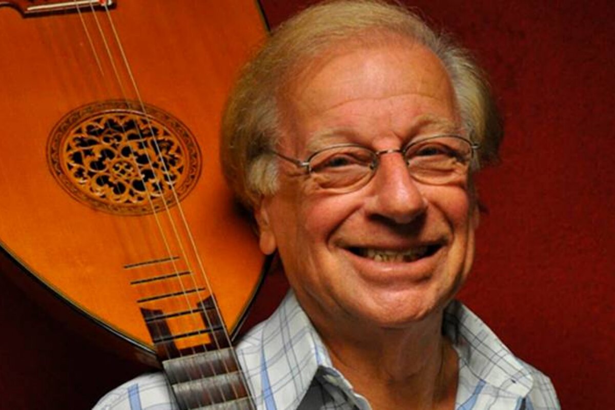 Juca Chaves com violão no ombro, sorrindo