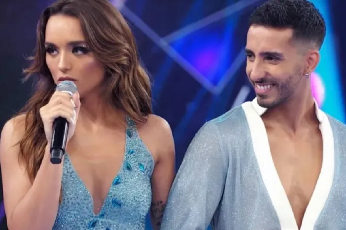 vestido azul, falando ao microfone ao lado do professor na Dança dos Famosos