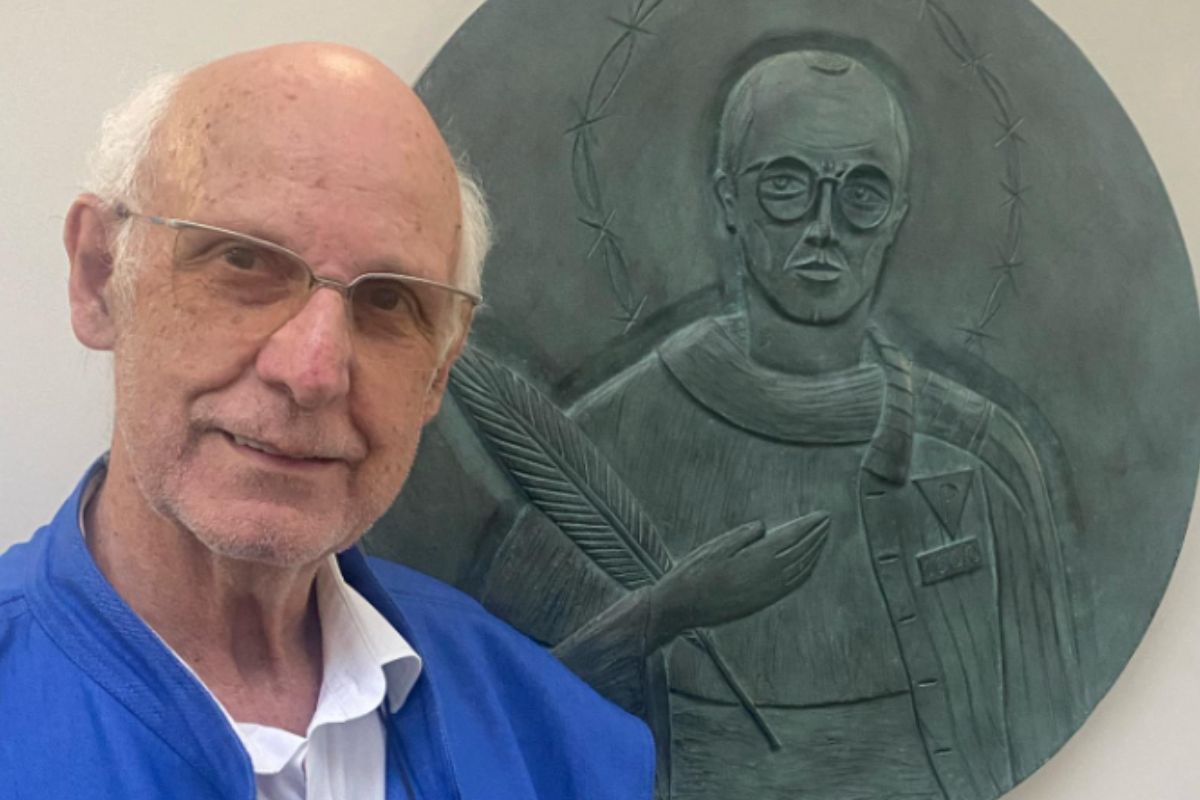 Padre Julio Lancelotti em frente ao Medalhão em homenagem a São Maximiliano Kolbe, na casa Santa Edith Stein