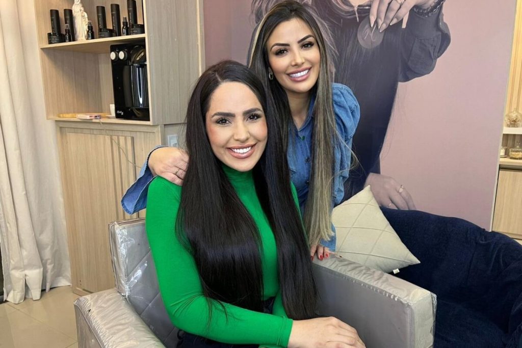 Perlla de cabelo escuro camisa verde, sentada ao lado da cabeleireira