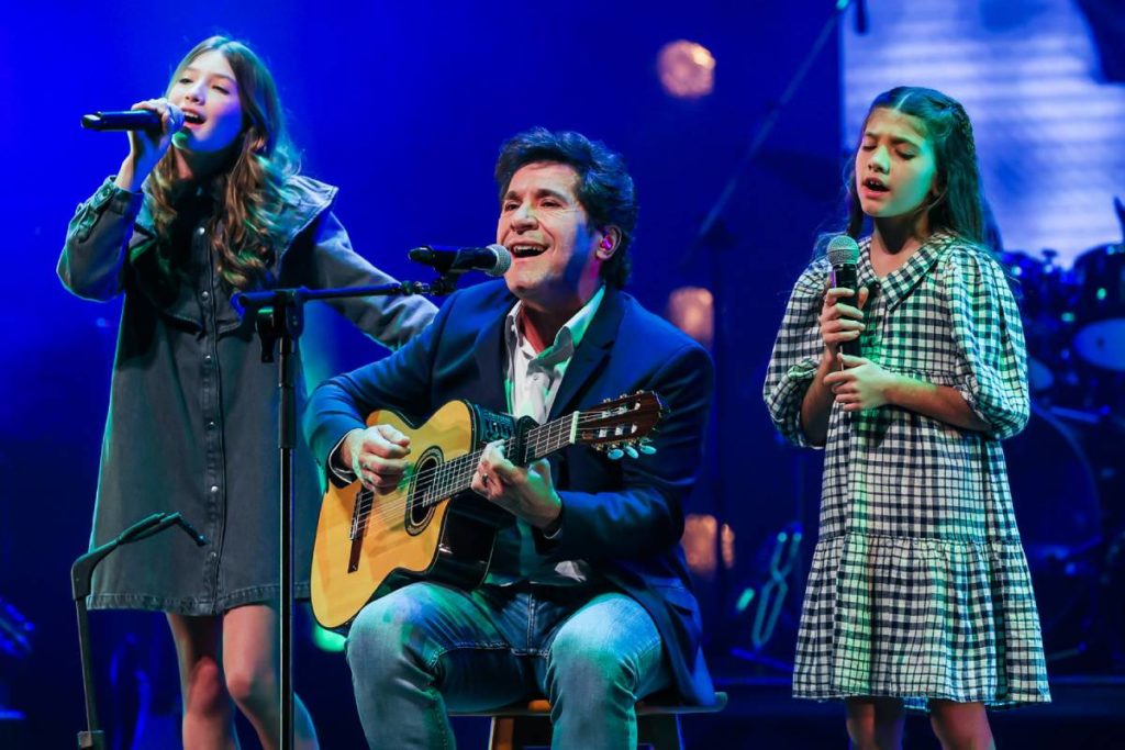 daniel tocando violão enquanto canta ao lado das filhas laura e luiza