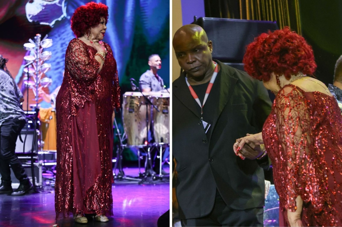 Alcione de vestido vermelho cintilante, deixando o palco amparada