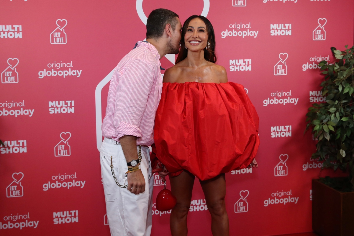 João Vicente de camisa rosa, calça branca, com e Sabrina Sato de vestido vermelho tomara que caia, em forma de coração