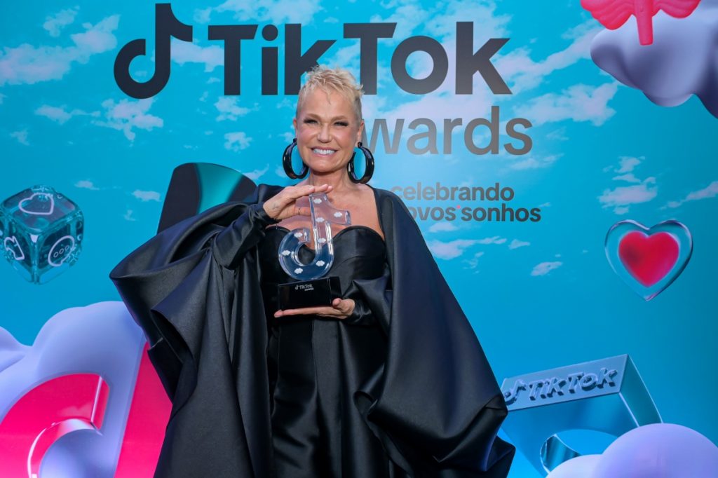 tik-tok-awards-xuxa-meneghel-homenageada-1024x682-1 Xuxa Meneghel de vestido preto, exibindo troféu