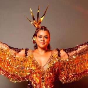 preta gil com roupas de carnaval e de braços abertos