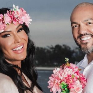 Gracyanne Barbosa de tiara de flores, segurando buquê com as mesmas flores, e Belo